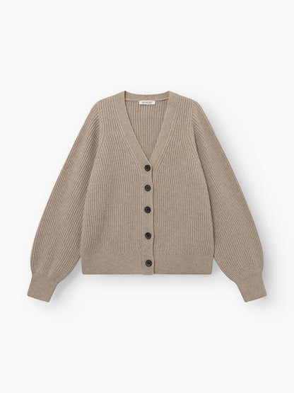 Die Strickjacke „Antonia Rib Beige“ ist eine beigefarbene Strickjacke mit Rippmuster, langen Ärmeln, einem V-Ausschnitt und schwarzen Knöpfen an der Vorderseite. Sie zeichnet sich durch eine klassische Rippstruktur aus und wird vor weißem Hintergrund gezeigt.
