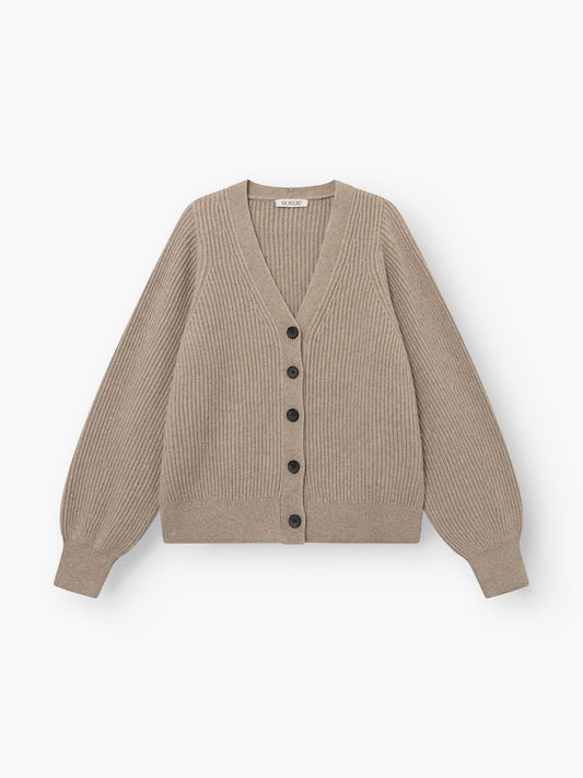 Die Strickjacke „Antonia Rib Beige“ ist eine beigefarbene Strickjacke mit Rippmuster, langen Ärmeln, einem V-Ausschnitt und schwarzen Knöpfen an der Vorderseite. Sie zeichnet sich durch eine klassische Rippstruktur aus und wird vor weißem Hintergrund gezeigt.