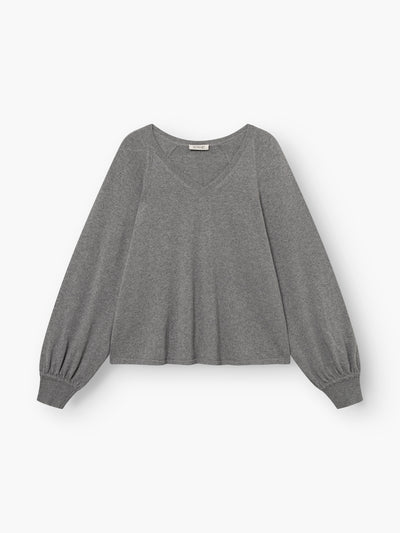 Der Pullover „Antonia V-Neck Grau“ ist ein langärmeliger, grauer Pullover mit V-Ausschnitt aus Merinowolle und gerippten Bündchen, der vor einem schlichten weißen Hintergrund abgebildet ist.