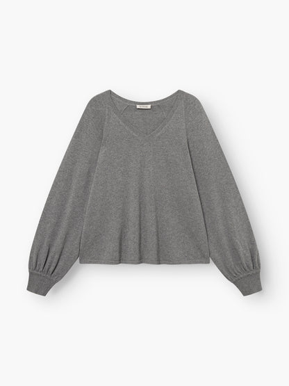 Der Pullover „Antonia V-Neck Grau“ ist ein langärmeliger, grauer Pullover mit V-Ausschnitt aus Merinowolle und gerippten Bündchen, der vor einem schlichten weißen Hintergrund abgebildet ist.