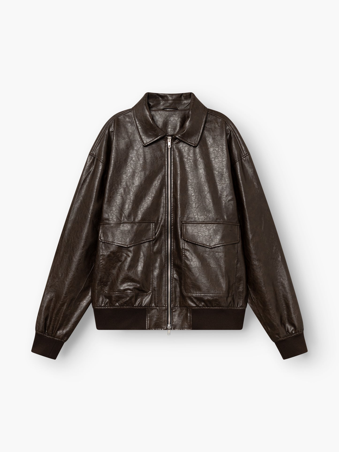 Eine Oversize-Jacke aus veganem Leder in Dunkelbraun mit einem Reißverschluss vorne, zwei großen Pattentaschen, einem klassischen Kragen sowie gerippten Bündchen und Saum, abgebildet auf weißem Hintergrund.