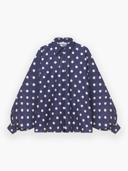 Die Antonia Dots Navy Ecru ist eine marineblaue Bluse in Übergröße aus weichem Baumwollvoile mit ecrufarbenen Punkten, voluminösen langen Ärmeln mit geknöpften Manschetten und einem klassischen Kragen. Hier auf weißem Grund abgebildet.