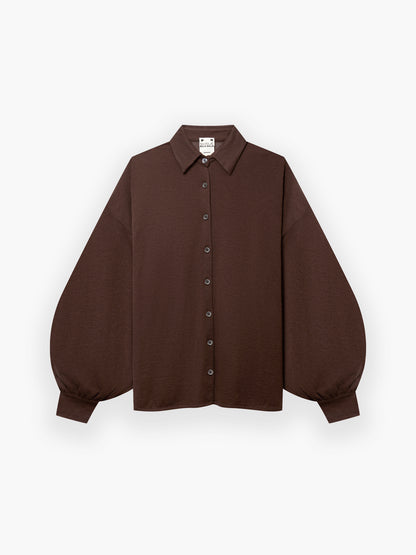 Die Bluse Antonia Cashmere Brown One Size von Ella Silla x SOSUE zeigt sich mit langen Ärmeln, einem spitzen Kragen und voluminösen Manschetten - für luxuriöse Eleganz auf weißem Grund.