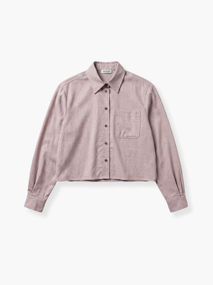 Das „Flanell Cropped Taupe“ ist ein hellviolettes, kurz geschnittenes Flanellhemd mit Kragen, langen Ärmeln, einer einzelnen Brusttasche und schwarzen Knöpfen, das flach auf einem weißen Hintergrund liegt.