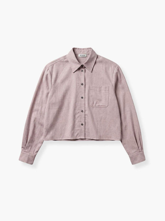 Das „Flanell Cropped Taupe“ ist ein hellviolettes, kurz geschnittenes Flanellhemd mit Kragen, langen Ärmeln, einer einzelnen Brusttasche und schwarzen Knöpfen, das flach auf einem weißen Hintergrund liegt.