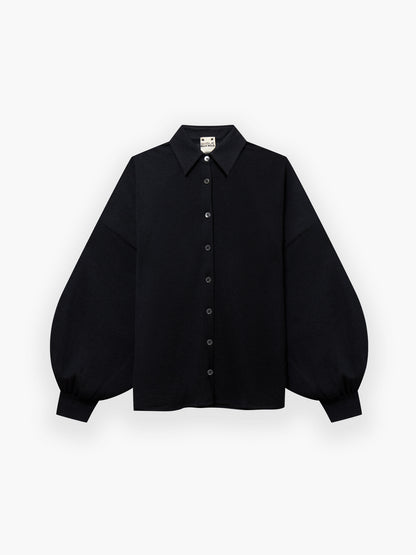 Die Bluse Antonia Cashmere Black One Size von Ella Silla x SOSUE präsentiert sich mit spitzem Kragen und voluminösen, langen Ärmeln mit gerafften Manschetten auf weißem Grund - eine Verkörperung luxuriöser Eleganz.