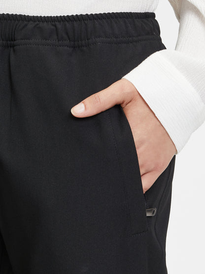 Eine Person in einem weißen langärmeligen Oberteil hat ihre rechte Hand in der Tasche der Hose Karoline Black, einer locker sitzenden, elastischen Bootcut-Damenhose - eine elegante Wahl für ein Business-Outfit.