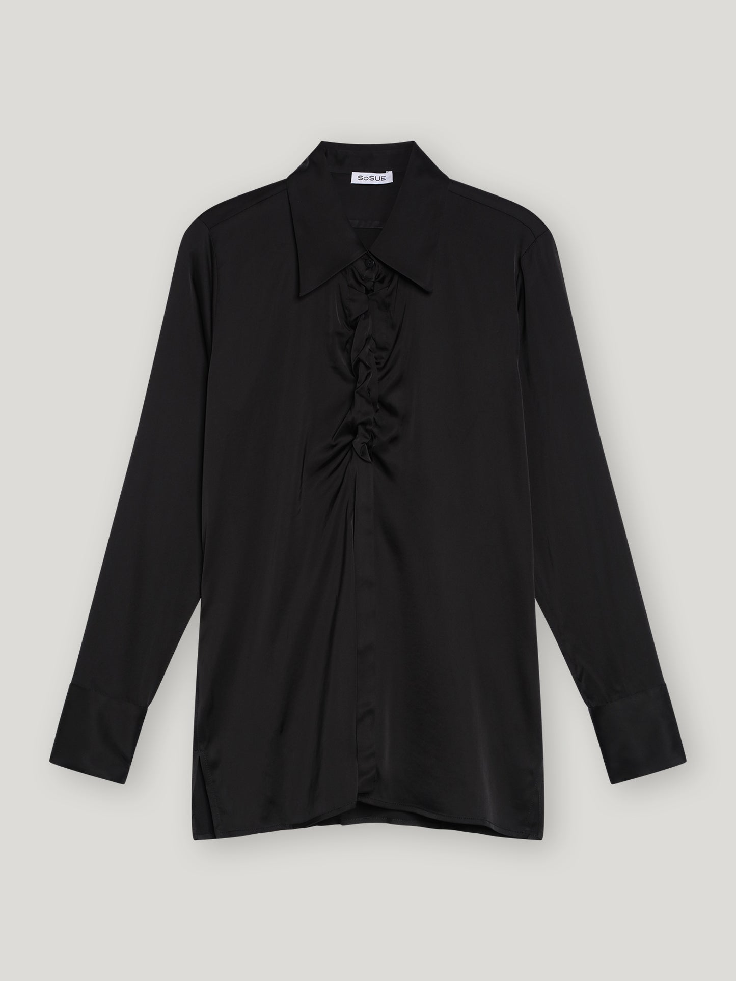 Die Bluse Ella Shiny Black ist eine schwarze Satinbluse mit klassischem Kragen, gerafften Details an der Vorderseite und tailliertem Schnitt. Sie ist flach auf einem hellgrauen Hintergrund ausgelegt.