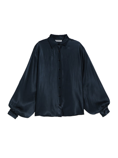 Die Bluse Antonia Shiny Slim Navy ist eine langärmelige Damen Oversized-Bluse mit geknöpfter Vorderseite, Rundhalsausschnitt und voluminösen Ärmeln mit geknöpften Manschetten auf hellgrauem Grund.