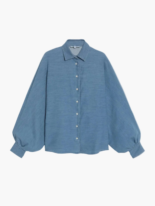 Eine locker sitzende, langärmelige Bluse Antonia Denim mit spitzem Kragen, geknöpfter Vorderseite und breiten Manschetten wird vor einem schlichten weißen Hintergrund präsentiert.