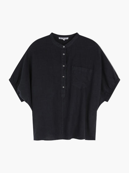 Die Bluse Cowboy Button Linen Black ist eine locker sitzende, kurzärmelige schwarze Leinenbluse Damen mit Mandarinkragen, Knopfleiste, Brusttasche und entspannter Silhouette - auf einem schlichten hellen Hintergrund.