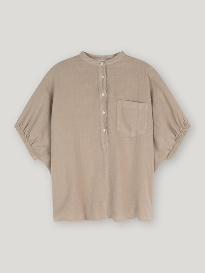 Ein lockeres, beigefarbenes Bluse Cowboy Button Leinenhemd mit Stehkragen, halber Knopfleiste und weißen Knöpfen, kurzen Ärmeln mit gerafften Manschetten und einer Brusttasche - auf weißem Grund abgebildet.
