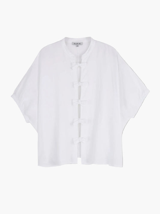 Die Bluse Cowboy Bow ist eine locker sitzende weiße Leinenbluse für Damen mit kurzen Ärmeln, Mandarinkragen und fünf traditionellen Knotenverschlüssen auf der Vorderseite. Auf hellgrauem Grund ist sie die ideale Wahl für Fans der nachhaltigen Mode.