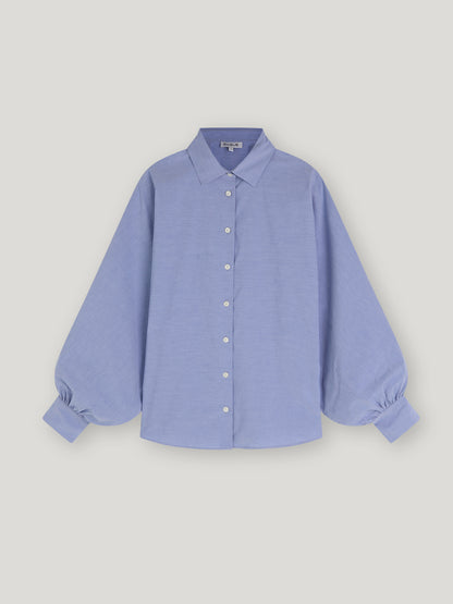 Bluse Antonia Slim Middleblue ist eine hellblaue Button-up-Bluse mit klassischem Kragen und langen, voluminösen Ballonärmeln, die an den Manschetten gerafft sind und so für einen Oversized-Look sorgen, auf einem schlichten weißen Hintergrund.