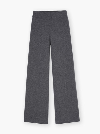 Die Hose Merino Grey ist eine dunkelgraue Hose mit weitem Bein aus weicher Merinowolle, die flach auf weißem Grund getragen wird und Komfort mit zeitlosem Stil verbindet.