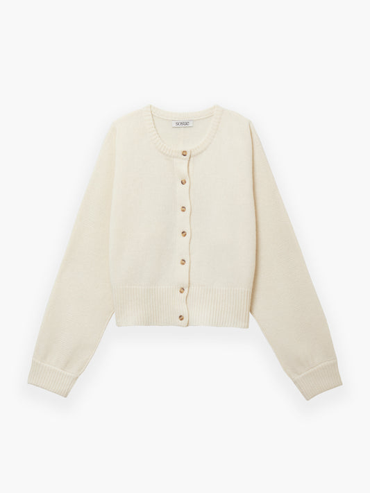 Die Jacke Cashmere OffWhite ist eine cremefarbene, langärmelige Strickjacke mit Rundhalsausschnitt, Rippbündchen an Ärmeln und Saum und Knopfverschluss vorne mit kleinen runden Knöpfen.