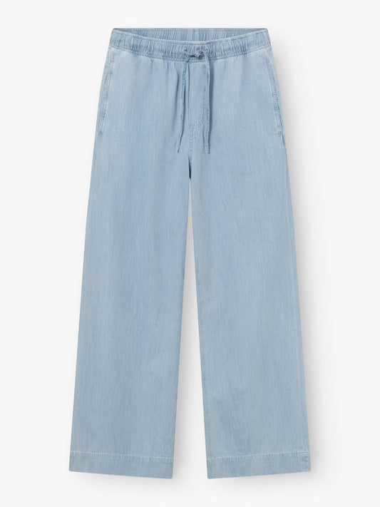 Die Anna Pants Light Denim ist eine hellblaue Jeanshose mit weitem Bein, elastischem Bund, Kordelzug, Seitentaschen und einer lockeren, knöchellangen Passform für lässigen Stil.