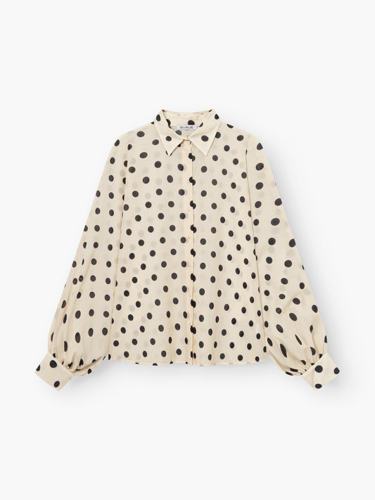 Die Antonia Dots Ecru Black ist eine cremefarbene Damen Statement-Bluse aus weichem Baumwoll-Voile mit schwarzen Punkten, geknöpfter Vorderseite, spitzem Kragen und voluminösen langen Ärmeln, die an den Handgelenken gerafft sind.