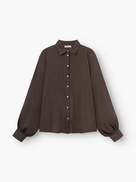 Die Antonia Cotton Brown ist eine locker sitzende, langärmelige, dunkelbraune Button-up-Bluse mit Kragen und breiten, gerafften Manschetten, die auf weißem Hintergrund abgebildet ist.