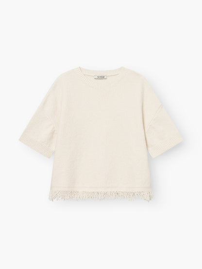 Das Aurora Fringe Panna ist ein cremefarbenes Strickshirt Damen aus einem weichen Bio-Baumwoll-Mix mit kurzen Ärmeln, Rundhalsausschnitt und Fransen am Saum - ein ideales Sommer-Top, hier auf weißem Grund.