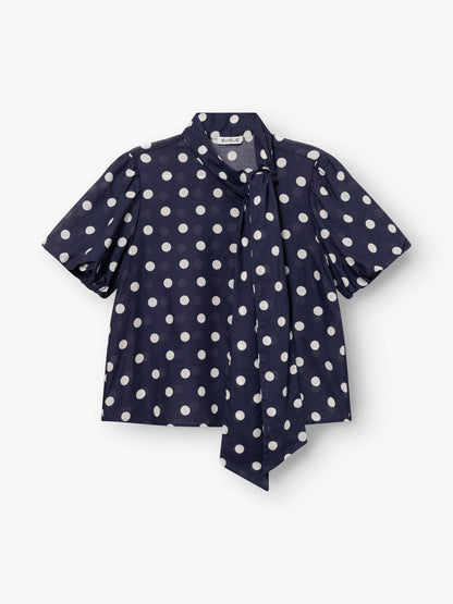 Bluse Bow Slim Dots in navy und off white mit kurzen Puffärmeln, weißen Tupfen und einer aufgesetzten Krawatte. Die Bluse liegt flach auf einem weißen Hintergrund.
