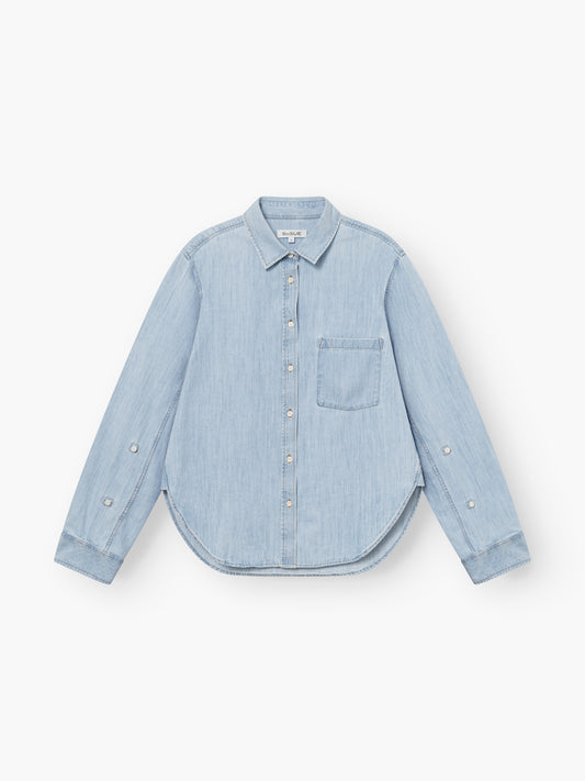 Die Bluse Classic Denim Denim ist ein hellblaues, langärmeliges Hemd mit Knopfleiste, linker Brusttasche und abgerundetem Saum, das flach auf weißem Grund liegt.