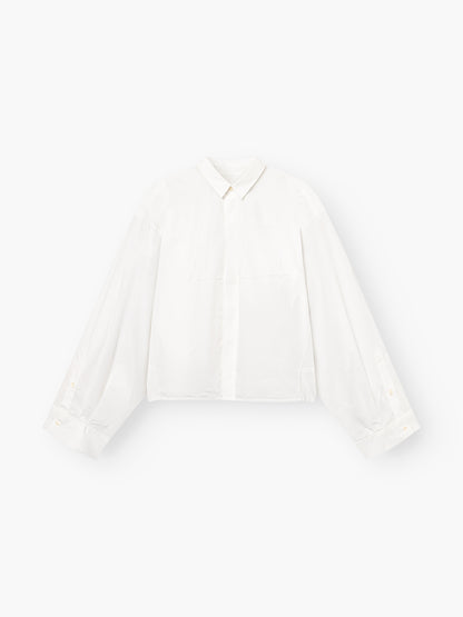 Die Blouse Bomber White ist eine weiße, langärmelige Button-up-Bluse mit Kragen und weiten, leicht gepufften Ärmeln, die vor einem einfarbig weißen Hintergrund gezeigt wird.