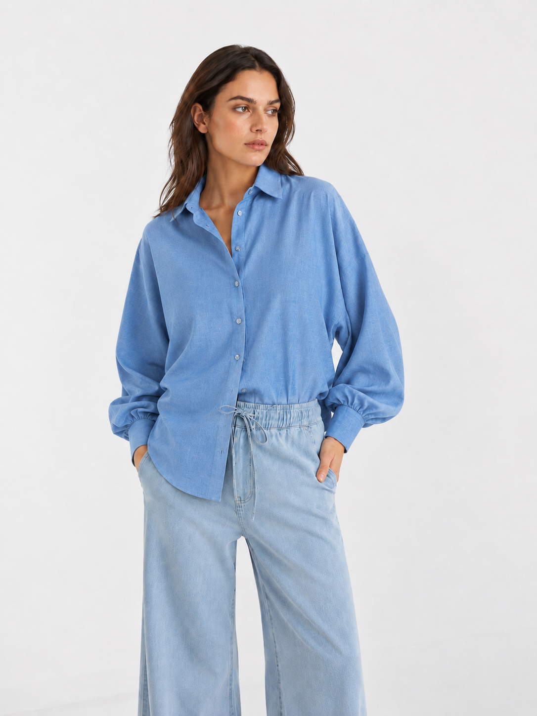 Eine Frau, die ein hellblaues Bluse Antonia Slim Flanell-Hemd mit ausgestellten Ärmeln und eine hellgewaschene Jeanshose trägt.