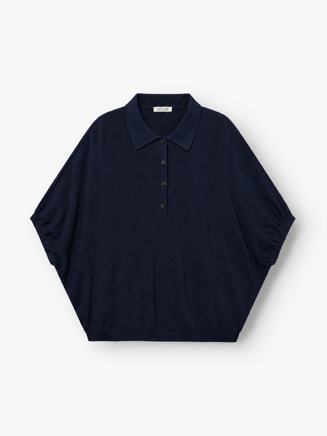 Kurzärmeliges „Cowboy Polo Knit Navy“-Hemd mit Kragen und Knopfleiste, das sich durch breite Ärmel im Fledermaus-Stil und eine lockere, weite Passform auszeichnet, flach auf weißem Hintergrund liegend. Dieses Design vereint Komfort und Stil zu einem mühelos schicken Look.