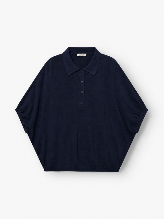 Kurzärmeliges „Cowboy Polo Knit Navy“-Hemd mit Kragen und Knopfleiste, das sich durch breite Ärmel im Fledermaus-Stil und eine lockere, weite Passform auszeichnet, flach auf weißem Hintergrund liegend. Dieses Design vereint Komfort und Stil zu einem mühelos schicken Look.