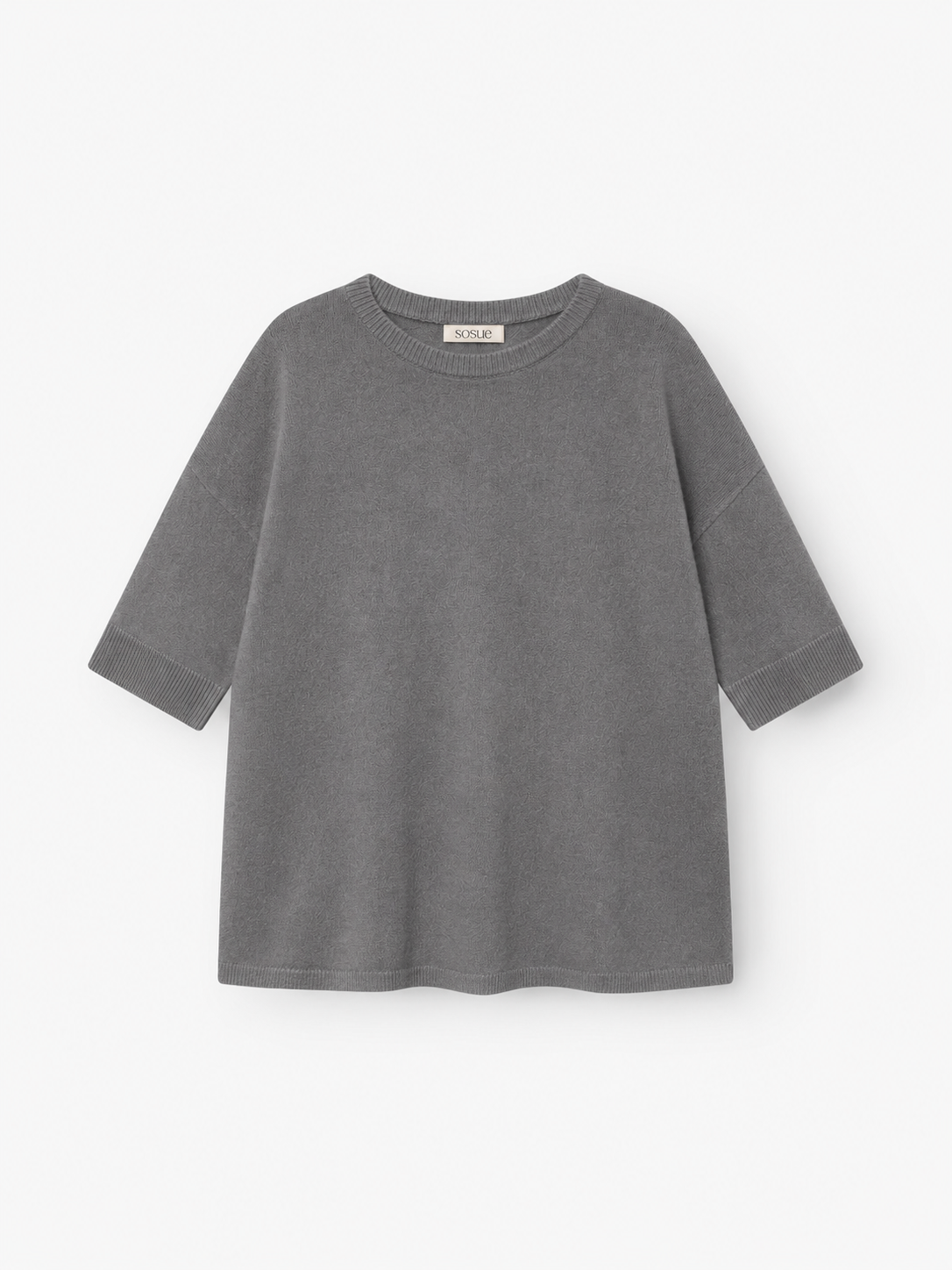 Ein graues Strick-T-Shirt „Aurora Anthra“ mit kurzen Ärmeln, lockerer Passform und rundem Ausschnitt, gefertigt aus weichem Strickstoff und flach auf weißem Hintergrund präsentiert.