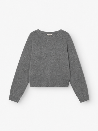 Der Pullover „Charly Anthra“ ist ein schlichter, langärmeliger Damenpullover aus meliertem, grauem Strick mit Rundhalsausschnitt sowie gerippten Bündchen und Saum, der flach auf weißem Hintergrund präsentiert wird. Dieser Pullover wurde aus einer weichen Mischfaser gefertigt, die an luxuriöse Merinowolle und Kaschmir erinnert, und bietet außergewöhnlichen Tragekomfort.