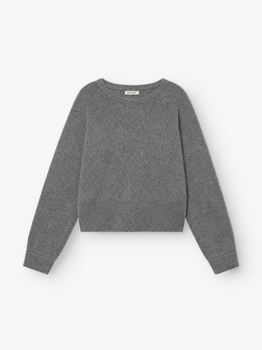 Der Pullover „Charly Anthra“ ist ein schlichter, langärmeliger Damenpullover aus meliertem, grauem Strick mit Rundhalsausschnitt sowie gerippten Bündchen und Saum, der flach auf weißem Hintergrund präsentiert wird. Dieser Pullover wurde aus einer weichen Mischfaser gefertigt, die an luxuriöse Merinowolle und Kaschmir erinnert, und bietet außergewöhnlichen Tragekomfort.