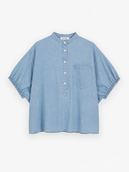 Hellblaue, kurzärmelige Bluse aus Cowboy-Button-Denim mit chinesischem Kragen, Knopfleiste, einer Brusttasche und elastischen Ärmelbündchen, abgebildet vor weißem Hintergrund.