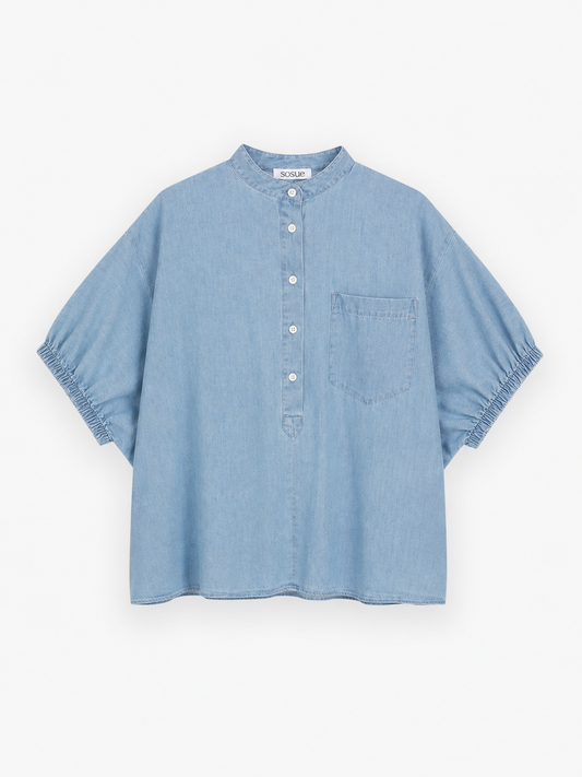 Hellblaue, kurzärmelige Bluse aus Cowboy-Button-Denim mit chinesischem Kragen, Knopfleiste, einer Brusttasche und elastischen Ärmelbündchen, abgebildet vor weißem Hintergrund.