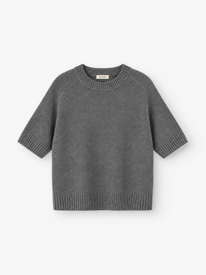 Joana T-Shirt: Ein graues, kurzärmeliges Strick-T-Shirt mit gerippten Bündchen, Saum und Kragen, gefertigt aus einer luxuriösen Merinowolle-Mischung und auf weißem Hintergrund abgebildet.