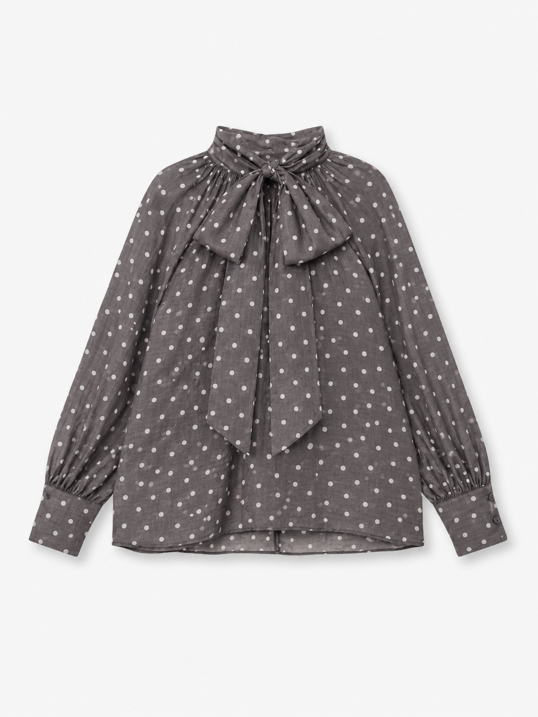 Eine langärmelige graue Bluse „Dotty Bow Grey Latte“ aus Baumwoll-Voile mit weißen Polka-Punkten, die sich durch einen hohen Kragen und eine große Schleife am Kragen auszeichnet. Diese elegante Bluse wird in Italien meisterhaft gefertigt und vereint klassischen Charme mit hochwertiger Handwerkskunst.