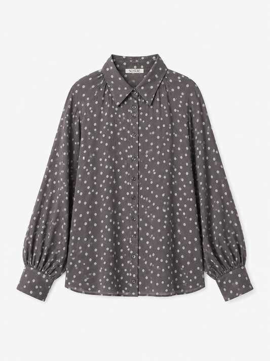 Die Bluse „Antonia Polka Dots Grey Latte“ ist eine langärmelige Bluse mit Knopfleiste, spitzem Kragen und weißen Polka-Punkten auf dunkelgrauem Hintergrund. Diese Damenbluse aus weichem Baumwoll-Voile verfügt über an den Ärmelbündchen geraffte Ärmel und wird in Italien meisterhaft gefertigt – ein Symbol für zeitlose Eleganz.