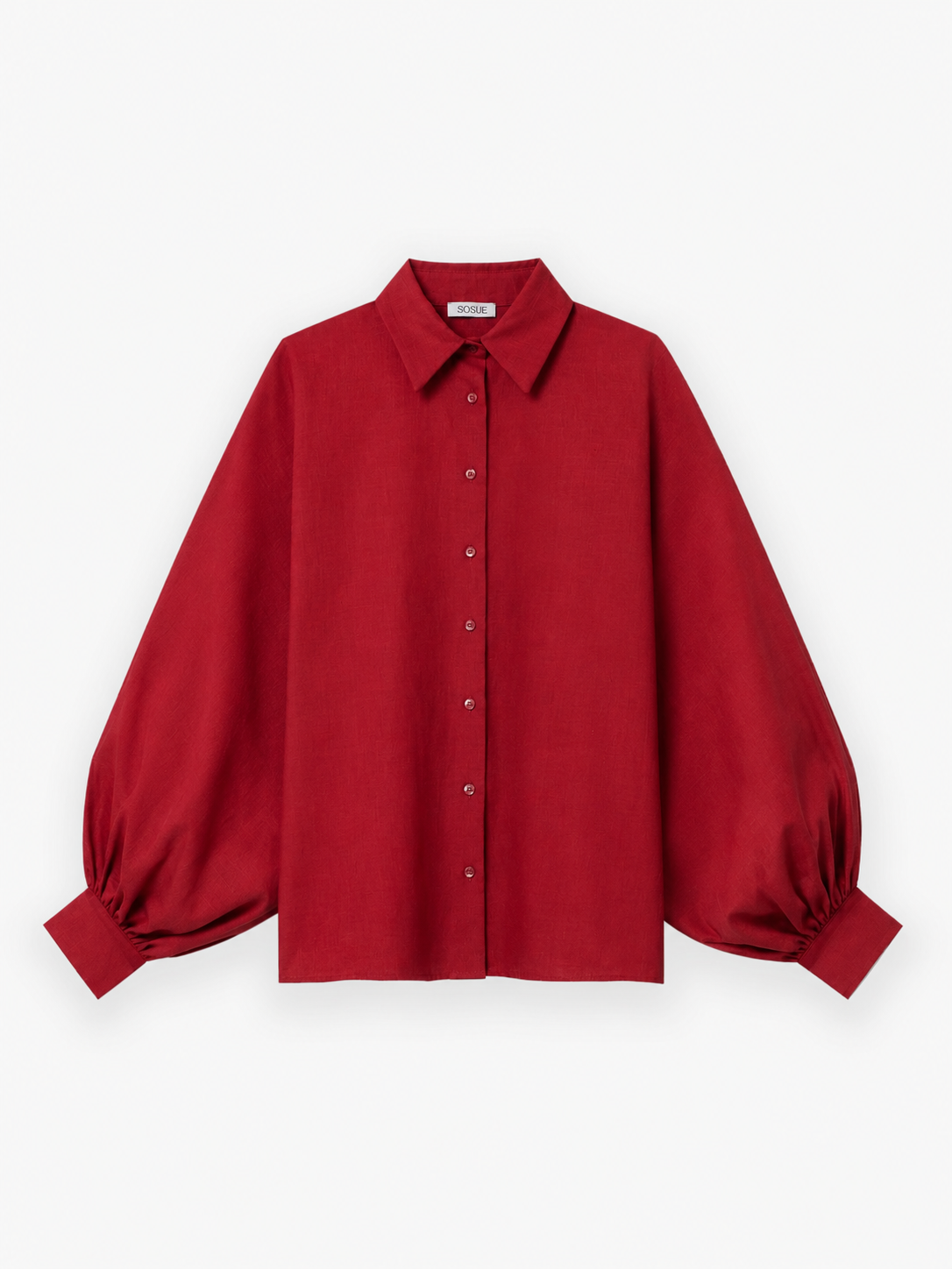 Die Bluse „Antonia Burgundy“ ist eine Damenbluse in einem satten Burgunderrot mit langen Ärmeln, einer Knopfleiste vorne und einem klassischen Kragen. Dieses elegante Modell mit voluminösen Puffärmeln aus weichem Baumwoll-Voile wird vor einem weißen Hintergrund präsentiert.