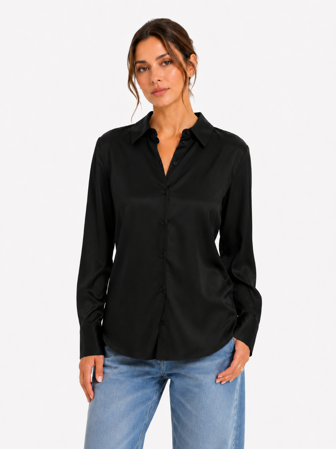 Eine Frau trägt die Bluse „Kaia Schwarz“ (hergestellt in Portugal), kombiniert mit einer hellblauen Jeans, und steht mit ausdruckslosem Gesicht vor einem schlichten weißen Hintergrund.