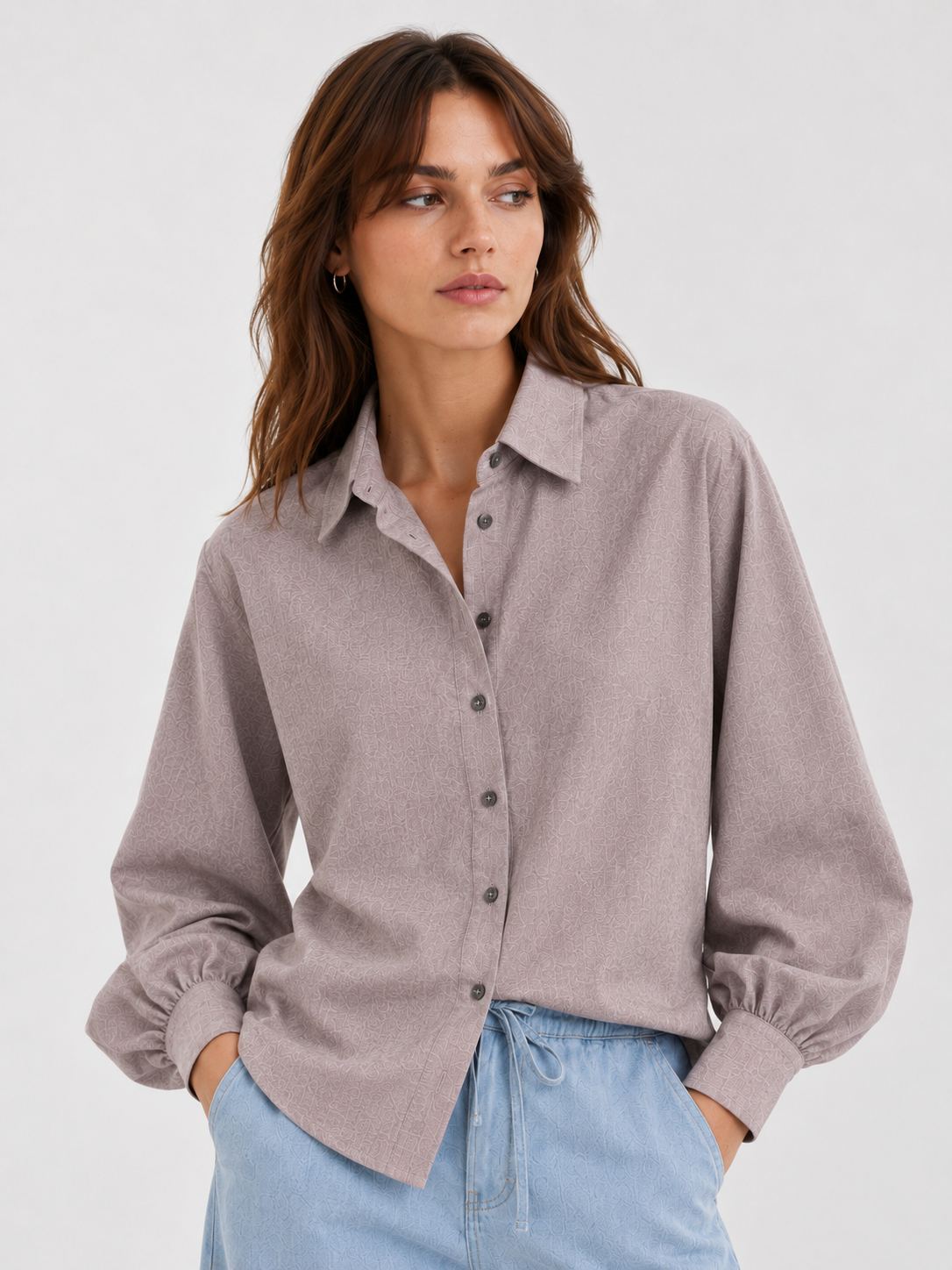 Frau, die eine Bluse Antonia Slim Flannel Taupe mit Knopfmanschetten und eine blaue Jeans trägt.