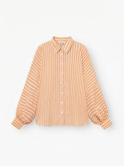 Das Bluse Antonia Rose Coral ist ein langärmeliges Button-up mit Kragen, orangefarbenen und weißen Längsstreifen und Ärmelmanschetten aus weichem Baumwoll-Voile, das auf einem einfarbig weißen Hintergrund abgebildet ist.