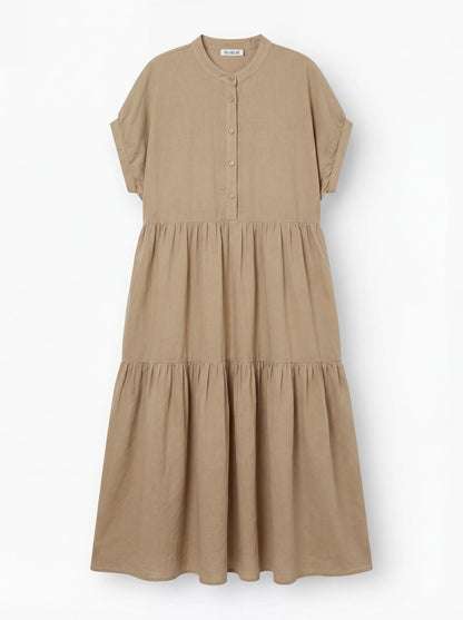 Das Kleid Cowboy Boho Sand ist ein beigefarbenes, kurzärmeliges Midikleid mit Knopfleiste, Stufenrock und Rundkragen aus leichtem Baumwoll-Voile auf weißem Grund.