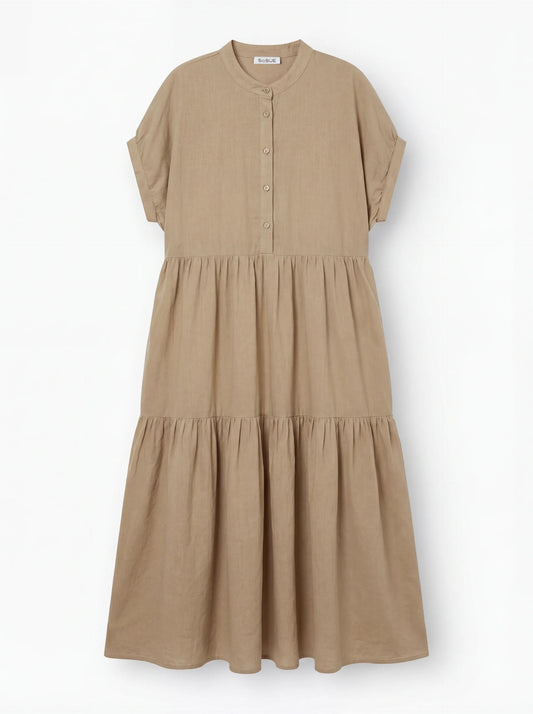 Das Kleid Cowboy Boho Sand ist ein beigefarbenes, kurzärmeliges Midikleid mit Knopfleiste, Stufenrock und Rundkragen aus leichtem Baumwoll-Voile auf weißem Grund.