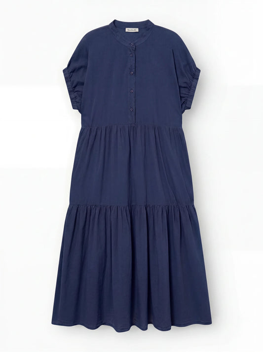 Das Kleid Cowboy Boho Navy ist ein locker sitzendes, kurzärmeliges Baumwollkleid in Marineblau mit gestuftem Rock, geknöpfter Vorderseite und rundem Halsausschnitt, abgebildet auf einem einfarbig weißen Hintergrund.