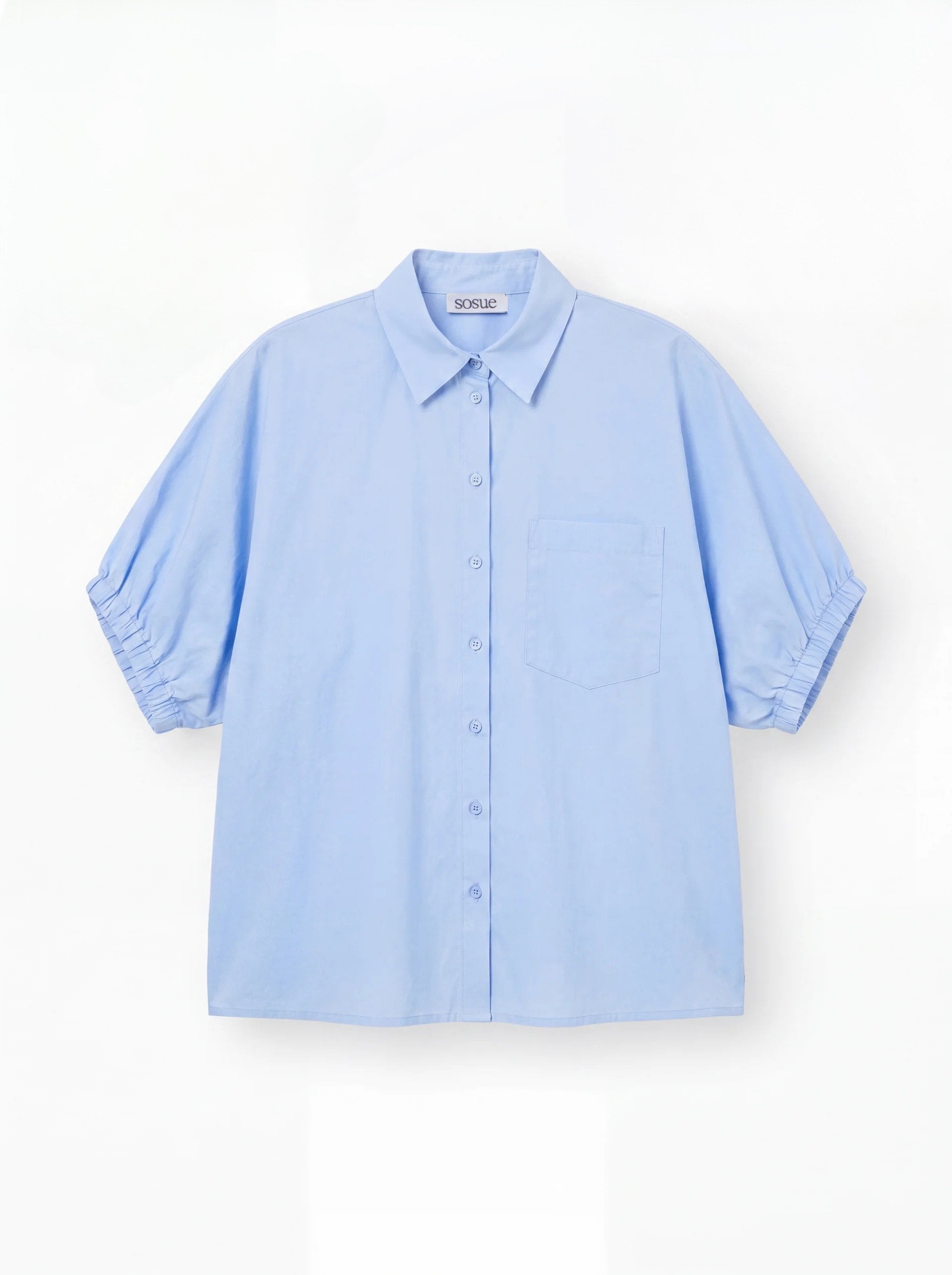 Das Cowboy Collar Voile Light Blue ist ein locker sitzendes, kurzärmeliges Button-up-Hemd mit Kragen und einer Brusttasche, das in Hellblau auf weißem Grund gehalten ist.