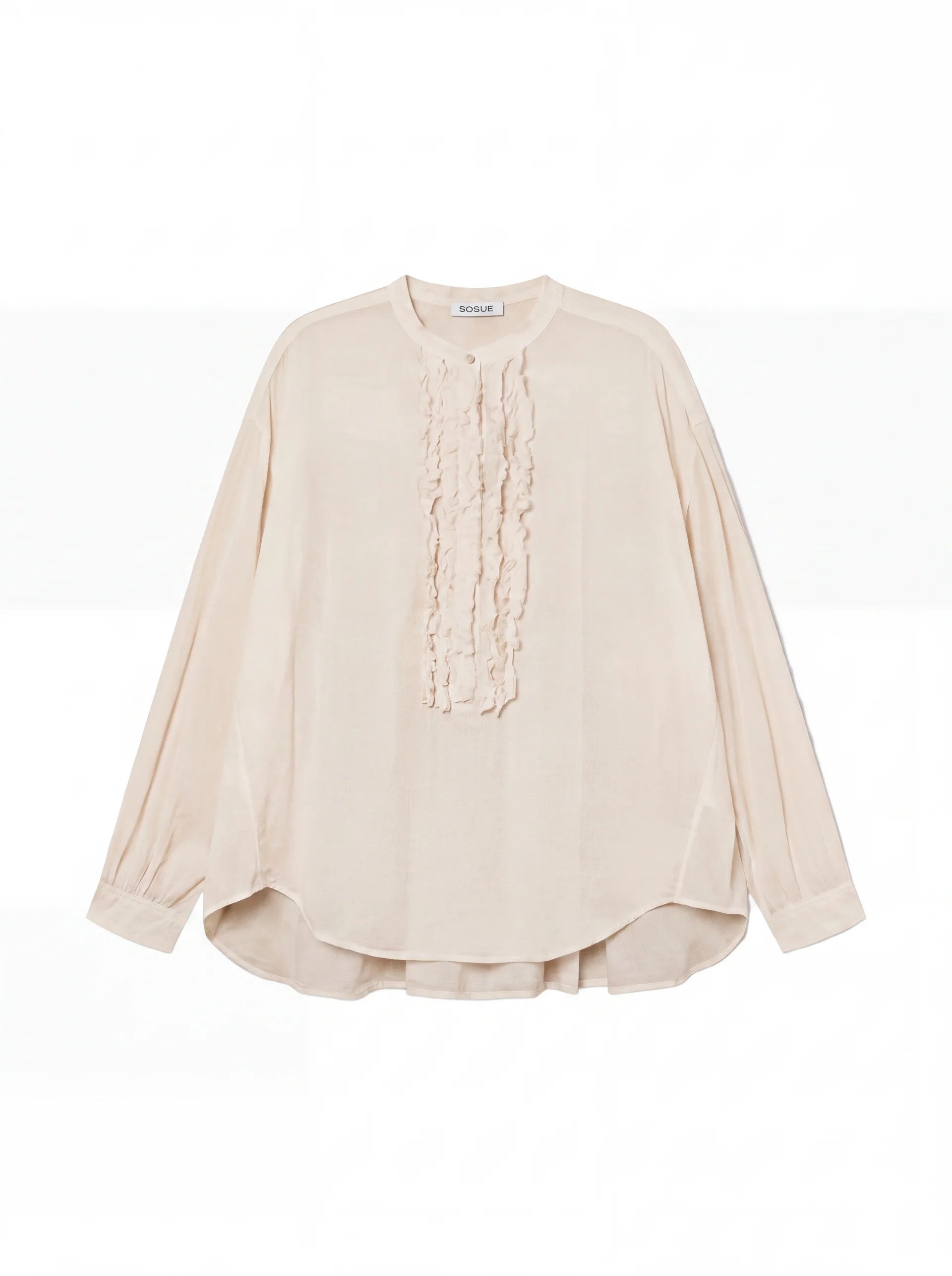 Die Bluse Bruna Beige ist eine langärmelige, cremefarbene Bluse mit Rundhalsausschnitt und zarten Rüschen auf der Vorderseite, die auf einem einfarbig weißen Hintergrund zu sehen ist.
