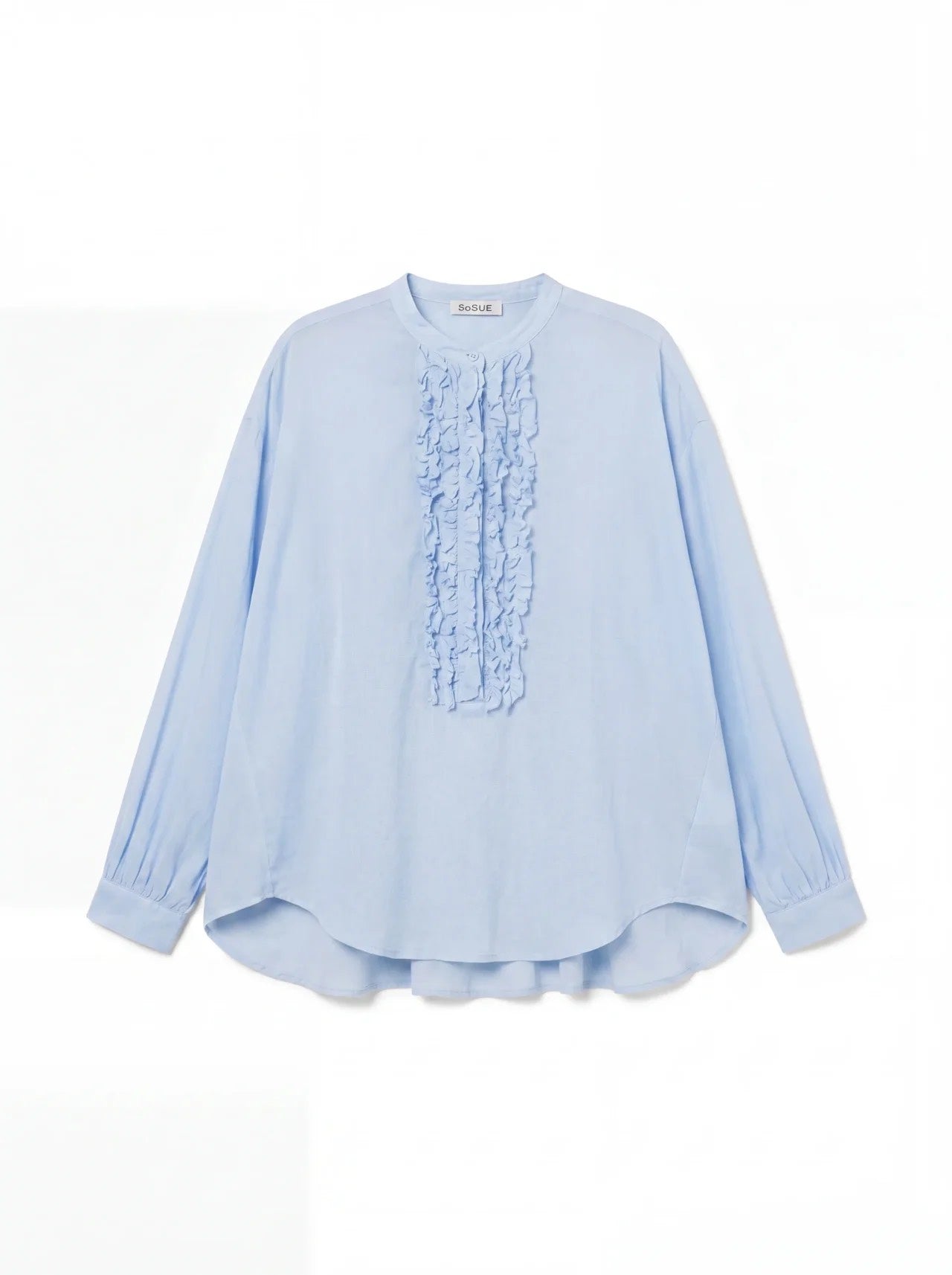 Die Bluse Bruna Light Blue ist eine langärmelige Sommerbluse mit Rundhalsausschnitt, gerüschten Details auf der Vorderseite, geknöpften Manschetten und einer lockeren Passform aus weichem Baumwoll-Voile.