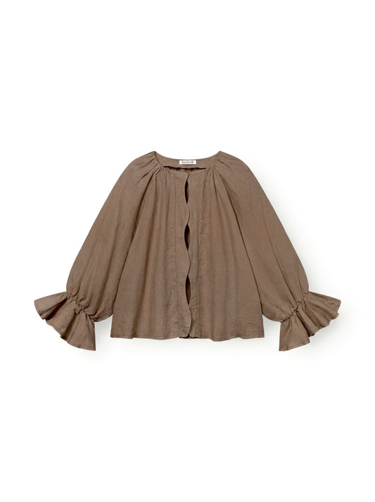 Die Bluse Wave Linen Soft Brown ist eine langärmelige, locker sitzende taupefarbene Bluse mit breiten Rüschenbündchen und einer gewellten Öffnung auf der Vorderseite, die auf einem einfarbig weißen Hintergrund abgebildet ist.