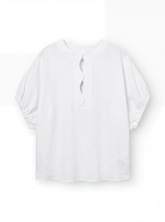 Die Bluse Cowboy Wave Linen White ist eine locker sitzende weiße Leinenbluse mit ellenbogenlangen gerafften Ärmeln, einem überschnittenen Schlüssellochausschnitt im Rücken und dezenten Wellendetail-Akzenten.